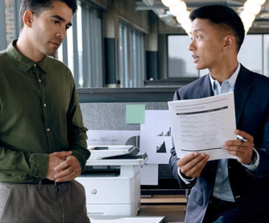 Imagem de dois executivos em um escrit&oacute;rio imprimindo em uma...